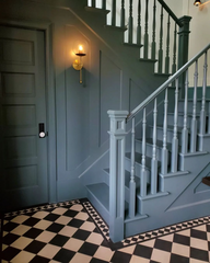 muted teal stairwell with black and white floors and a large gold sconce.  Modern victorian style. Eclectic style in an old home with modern touches