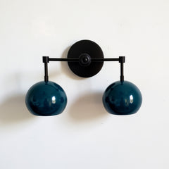 mid century modern inspired light with dark teal shades and matte black hardware.  The Double Loa sconce is a two light sconce that comes in fun colored shades and three metal options.