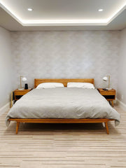 Neutral Bedroom design with a midcentury inspired wood platform bed, Mid century modern inspired table lamps, neutral beige wallpaper, and a neutral rug.