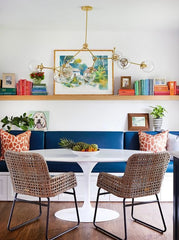 Modern kitchenette with tulip table, natural chairs, blue buffet bench, modern brass light fixture, colorful books, and cute art