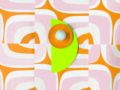 This Kin Sconce doesn’t whisper—it shouts. A neon chartreuse backplate, orange peel disc, and soft white bulb pop against a vintage-inspired pink-and-orange graphic wallpaper that channels pure 1970s roller rink bliss.