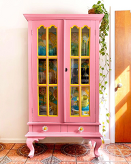 Daisy drawer pull on a pink cabinet that has been painted with yellow trim and wallpaper on the inside