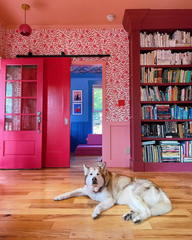 Monochrome Pink on Pink entry wall and living room with dark pink shelves, bright pink doors, light pink ceiling and wall trim, with a maximalist wallpaper.