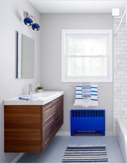 Blue and chrome two light wall sconce in a mid century modern bathroom renovation with hints of blue