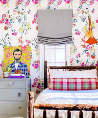 Colorful bedroom with a Cora sconce, floral wallpaper, rustic bed, and modern art
