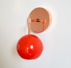 Copper and orange red mid century inspired wall sconce with an eyeball globe shade modern design for bathroom or bedroom lighting children decor
