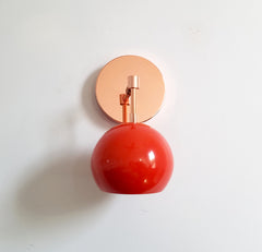 Copper and orange red mid century inspired wall sconce with an eyeball globe shade modern design for bathroom or bedroom lighting children decor