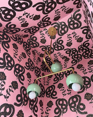 green and brass chandelier in a pink wallpapered bathroom