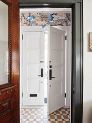 Entryway chandelier in pastel blue and brass in an old home with tiled floors and marbled wallpaper