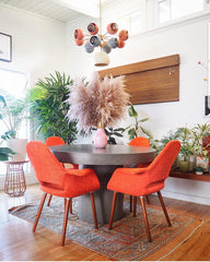mid century modern dining room with Solaris Chandelier, concrete dining table, and orange dining chairs