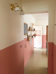 Hallway with pink wainscotting and a white and brass wall sconce