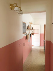 Hallway with pink wainscotting and a white and brass wall sconce