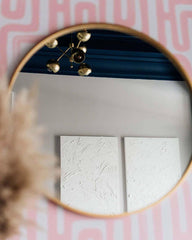 Brass chandelier against a navy ceiling with pink patterned wallpaper and white walls
