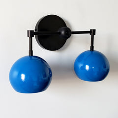 blue and black two light midcentury modern inspired wall sconce lighting with globe shades.  Fun colorful lighting for bathroom renovations.