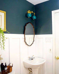 Green bathroom with a double loa wall sconce in green and brass