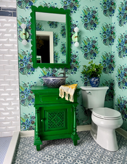 Mint and brass sconce on floral check wallpaper in a bold colorful bathroom