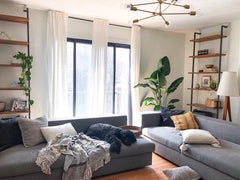 Neutral minimalist living room with industrial style shelving and a brass Napoleon chandelier