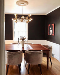 Brass floral chandelier in a black and white dining room with velvet bucket chairs.  Simple ceiling medallion