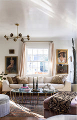 Boho living room with neutral sofa, modern floral chandelier, vintage coffee table