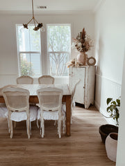 White vintage style dining room with a small brass floral chandelier
