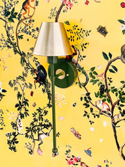 Olive green and brass wall sconce on a yellow monkey print wallpaper