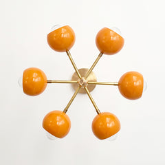 orange and brass midcentury modern style sconce or flushmount style ceiling light.  Great lighting for nurseries or kid related spaced.  Colorful and modern style light fixture.
