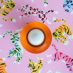 bright orange wall sconce on colorful pink wallpaper with tigers and leopards in rainbow colors