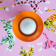 bright orange wall sconce on colorful pink wallpaper with tigers and leopards in rainbow colors