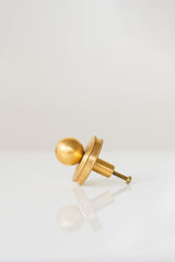 Close-up of the Phillip Drawer Pull, a round solid brass cabinet knob with a 1-inch ball and detailed beaded backplate, installed on a dark wood drawer. Ideal for traditional, transitional, or vintage-inspired kitchens, dressers, and bathroom vanities. A timeless furniture hardware upgrade handcrafted from solid brass with a warm golden finish.