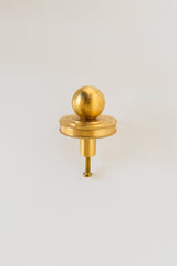 Close-up of the Phillip Drawer Pull, a round solid brass cabinet knob with a 1-inch ball and detailed beaded backplate, installed on a dark wood drawer. Ideal for traditional, transitional, or vintage-inspired kitchens, dressers, and bathroom vanities. A timeless furniture hardware upgrade handcrafted from solid brass with a warm golden finish.