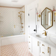 White pink and brass bathroom with pink floor, white subway tile, large marble vanity, and two brass and pink sconces