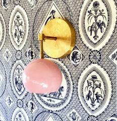 pink and brass Loa sconce on navy blue and white wallpaper
