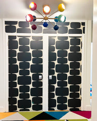 Bold and geometric inspired space with a black and white wallpaper and rainbow chandelier
