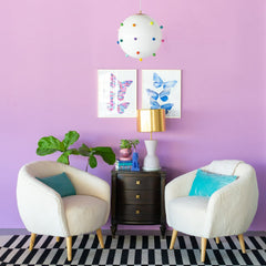 light purple living room with white boucle chairs, black and white rug, and wood side table with a cream and brass table lamp