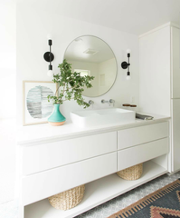 Black public belt sconces next to a round mirror in this california style bathroom remodel