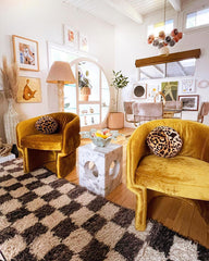 Eclectic living room with mustard velvet chairs, geometric accents, and solaris chandelier