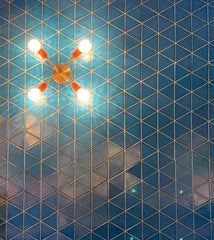 Brass and orange light fixture on a blue geometric tile wall