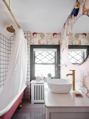 Funky modern bathroom with nude busts, pink clawfoot tub, and bright blue wall sconce