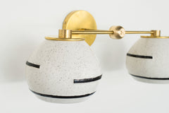 boho-inspired handmade wall sconce with speckled shades, black lines, and more.