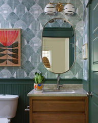 Organic modern two light wall sconce with speckled ceramic shades that have an accent line around the perimeter.  Featured in a traditional organic inspired bathroom with green geometric patterns wallpaper