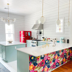Colorful kitchen with floral wallpaper, art deco pendants, and a modern chandelier over the island.  Features mint cabinets and a retro red refrigerator