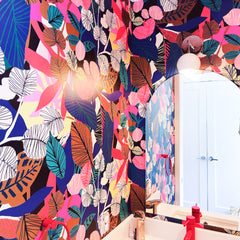 Colorful kids bathroom with rainbow jungle wallpaper, a red faucet, and a white and chrome loa sconce by Sazerac Stitches
