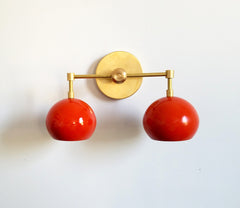 orange and brass modern wall sconce with two globes shades