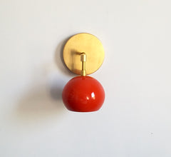brass and flame orange single light sconce with a globe eyeball shade
