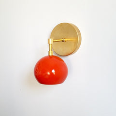 modern wall sconce made of raw brass and bright orange shade