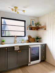 Neutral Kitchenette area with dark cabinets, white tile awlls, brass accents, and wood details