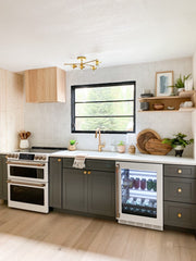 Neutral Kitchenette area with dark cabinets, white tile awlls, brass accents, and wood details
