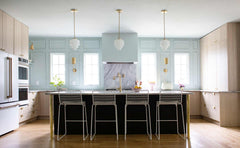pale wood and pastel blue kitchen renovation with modern cabinetry, brass details, and art deco inspired  pendant lighting