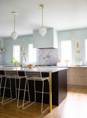 pale wood and pastel blue kitchen renovation with modern cabinetry, brass details, and art deco inspired  pendant lighting