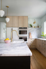 pale wood and pastel blue kitchen renovation with modern cabinetry, brass details, and art deco inspired  pendant lighting